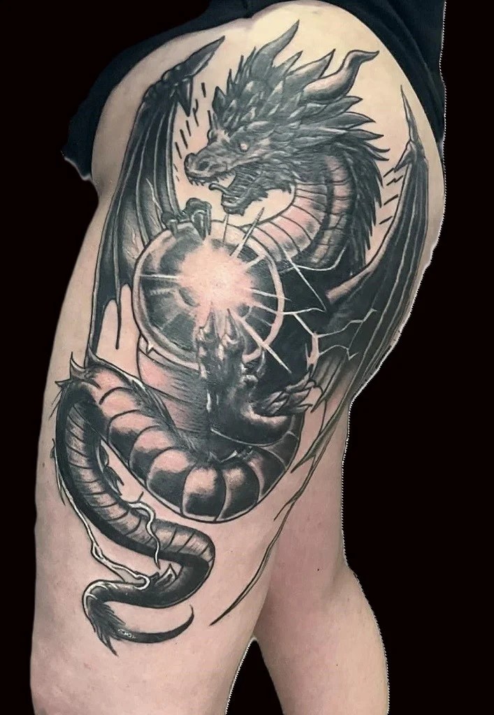 Tatouage en noir d'un dragon tenant une sphère lumineuse